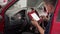 Auto electrician uses OBD2 scanner and tablet for car diagnostics. Mechanic checks vehicle engine codes in workshop