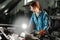 auto locksmith girl inspects the engine of the car illuminating the light of the lamp. Garage or auto repair shop and a