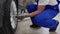 Auto mechanic in blue uniform tightens cars alloy wheel with torque wrench at modern auto repair shop. Skilled