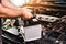 A auto mechanic carries a replacement car battery