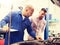 Auto mechanic with clipboard and man at car shop