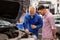 Auto mechanic with clipboard and man at car shop