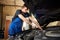 Auto mechanic in dirty work uniform repairs car in garage