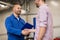 Auto mechanic and man shaking hands at car shop