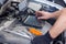 Auto mechanic with protective mask diagnosing car with black laptop
