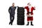 Auto mechanic and Santa gesturing thumb up and leaning on a pile of tires
