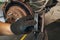 An auto mechanic shows the degree of wear of an old brake pad compared to a new one against the background of a car brake disc