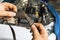 An auto mechanic shows a torn timing belt with worn teeth against the background of an open car hood