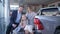 Auto shop, portrait of happy family with daughter chooses car and consult with each other while sitting in trunk at