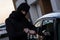 Auto thief in black balaclava trying to break into car