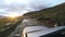 Auto travel: SUV rides on a high mountain road after rain at sunset over a river. POV - Point of view of a car moving on