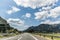 Autobahn or highway with a bridge in the mountains with clear marking surrounded by vibrant green trees under blue sky. Mountain