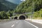 Autobahn or highway with a bridge in the mountains with clear marking surrounded by vibrant green trees under blue sky. Mountain