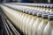 Automated equipment filled with rows of plastic milk containers on a conveyor belt