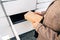 Automated locker. Parcel courier box in woman hands at post delivery automat terminal. Courier Puts Cardboard Package