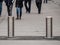 Automatic cylindrical barriers on the pedestrian zone against the background of blurry feet of pedestrians