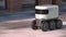 Automatic delivery robot driving down the morning street after rain