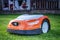 Automatic lawn robot mower moves on the grass, lawn. Close up side view with blurry background