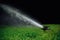 Automatic lawn sprinkler spraying water over golf course green grass