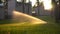 Automatic lawn sprinkler at sunset. Watering the lawn on the site.