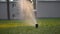 Automatic lawn sprinkler at sunset. Watering the lawn on the site. Slow motion.