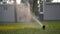 Automatic lawn sprinkler at sunset. Watering the lawn on the site. Slow motion.