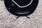 Automatic robot vacuum cleaner in black on gray shag carpet. New modern technologies for apartment cleaning. smart home electronic