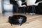 Automatic robot vacuum cleaner in black on wooden floor. New modern technologies for apartment cleaning. smart home electronic