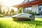 Automatic robotic lawn mower on a green lawn with modern house in background at sunny day