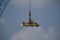 Automatic spreader of an industrial crane hanging in the air with blue sky background