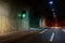 Automobile auto dark car tunnel with white arrows on asphalt showing way direction. Emergency exit sign with many lights