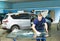 Automobile glazier cleaning car windscreen or windshield in service garage