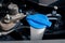 Automobile Maintenance. Windshield washer fluid cap with blue color in the engine room of car