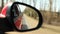 Automobile in motion. View in the rear view side mirror of a auto, driving a red car along the track