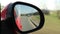 Automobile in motion. View in the rear view side mirror of a auto, driving a red car along the track