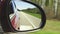 Automobile in motion. View in the rear view side mirror of a auto, driving a red car along the track