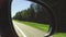 Automobile in motion. View in the rear view side mirror of a auto, driving a red car along the track