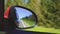 Automobile in motion. View in the rear view side mirror of a auto, driving a red car along the track