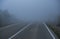 Automobile road in the mountains descending into clouds and fog in late autumn