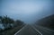 Automobile road in the mountains descending into clouds and fog in late autumn