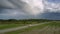 Automobiles drive slowly along gray asphalt road aerial view