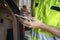 Automotive repairman with dirty hands makes notes in a small notebook standing by back of a car with hatchback open - Closeup and