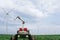 Autonomous robot harvester with robotic arm is working on a field with wind turbines.