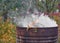 Autumn activity in garden, burning leaves, branches and dry grass in a old rusty barrel. Air pollution from farmers in the