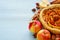 Autumn apple pie on the wooden board decorated with fresh apples, hazelnuts, spices - anise, cinnamon on the gray kitchen table