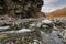 Autumn arctic landscape. A stream in a mountain gorge among the rocks.