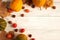 Autumn backdrop with autumn leaves, nuts, yellow and yellow-green little pumpkins, little red apples on an old white wooden table