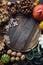 Autumn background with decorative pumpkin, acorns, nuts, greens, autumn leaves and wooden board with space for text on dark stone