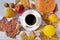 Autumn background of dry leaves with a white porcelain cup of coffee, pumpkin, lemon, ripe nectarines and walnuts