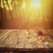 Autumn background of fallen leaves over wooden table and forest backgrond with lens flare and sunset
